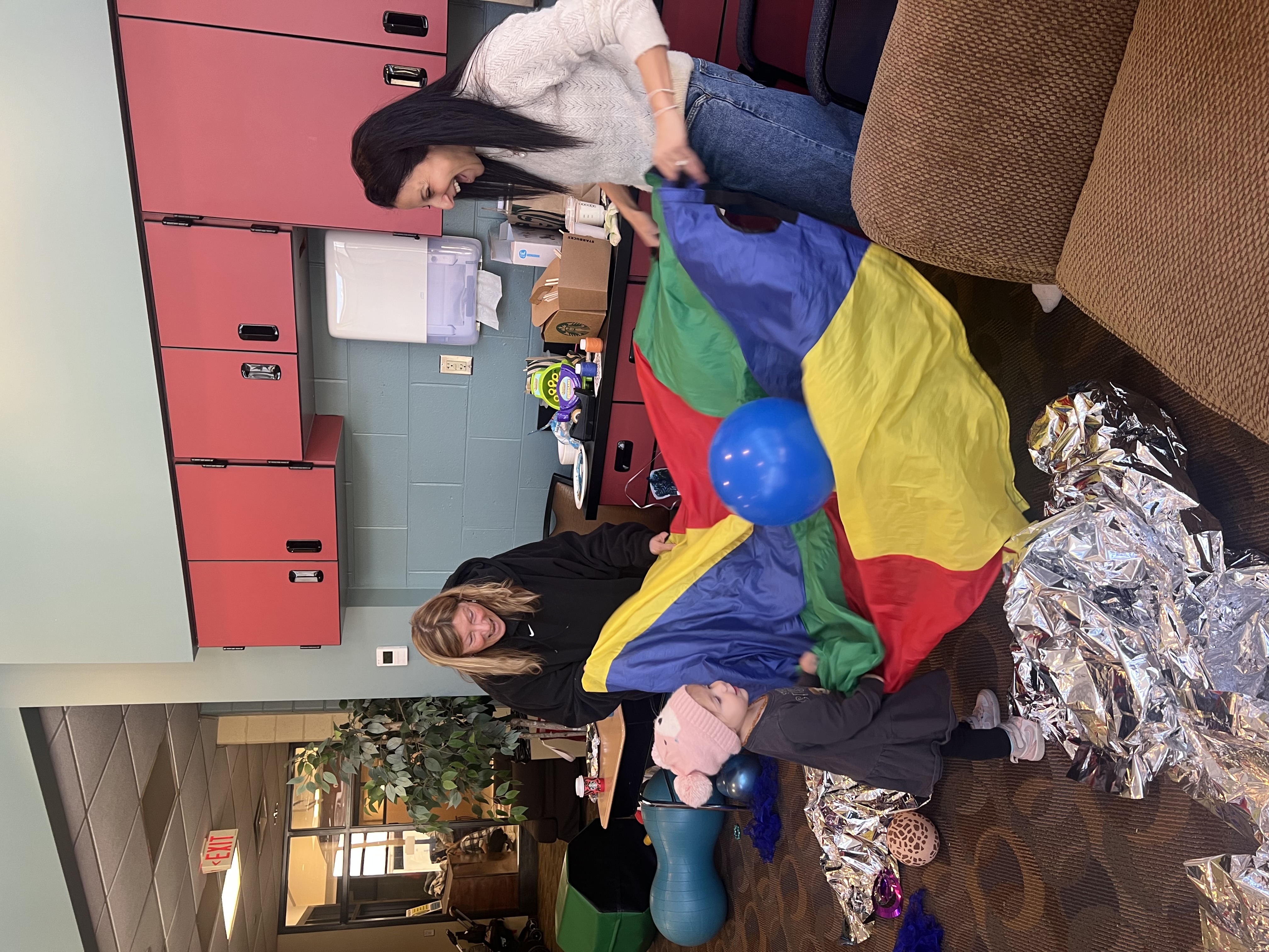 Rebeca and a caregiver engaging a child during a playful occupational therapy session