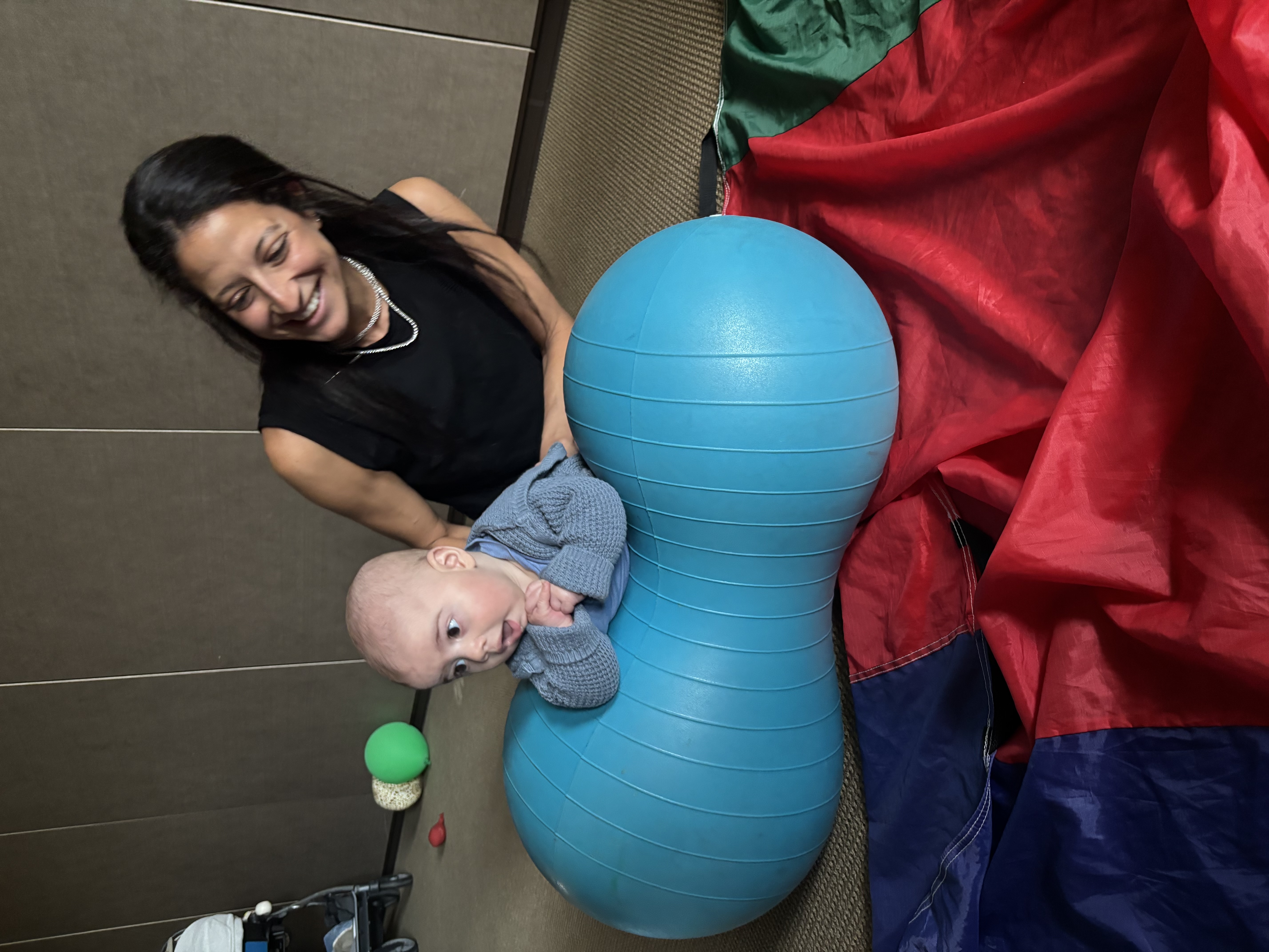 Rebeca guiding a baby through movement on a peanut therapy ball during an early development session